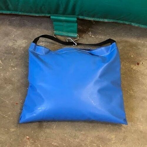Blauwe waterzak met zwarte draagband naast de rand van een springkussen